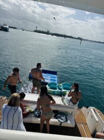 A lively group enjoys a fun day on the water, preparing to use a floating mat while soaking up the sun — perfect for summer parties and water activities.