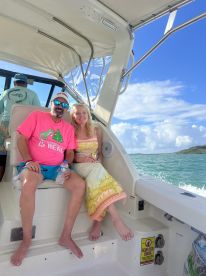 A couple relaxes on a boat, enjoying the sunny weather and beautiful water views — perfect for a romantic day on the water.