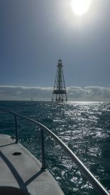 A stunning view of a lighthouse standing tall against the backdrop of a shimmering ocean, perfect for capturing the essence of a boating adventure.