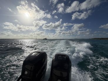 A dynamic view of a speedboat in motion, leaving a wake on the shimmering water under a bright sky — perfect for showcasing the thrill of boating adventures.