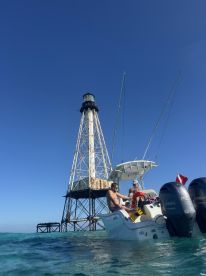 A group enjoys a day on the water near a historic lighthouse, showcasing the perfect blend of adventure and relaxation while boating.