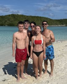A joyful group of family members poses on the beach, capturing a memorable moment in a tropical paradise — perfect for family vacations and beach outings.