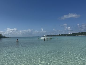 A group enjoys a fun day at the beach, swimming in shallow waters near a pontoon boat — perfect for sandbar stops and family outings.