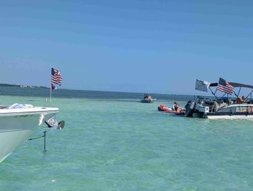A vibrant scene at a sandbar with multiple boats enjoying the sun and water, perfect for a day of fun and relaxation on the water.