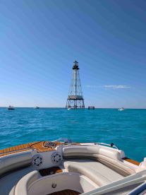 A stunning view from a boat showcasing a lighthouse against a backdrop of vibrant turquoise waters — perfect for scenic boating adventures.