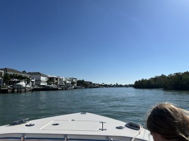 A scenic view from the bow of a boat navigating through a picturesque waterway lined with beautiful homes, capturing the essence of a relaxing day on the water.