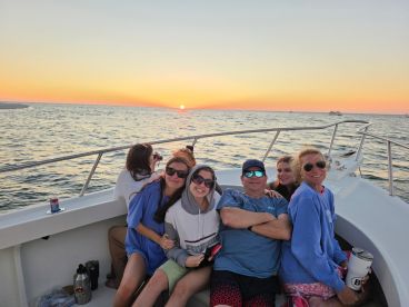 A cheerful group of friends enjoys a sunset cruise on a boat, capturing the perfect moment of camaraderie against a stunning backdrop.