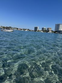 A scenic view of a boat cruising through crystal-clear waters, with a vibrant coastline in the background — perfect for showcasing beautiful boating destinations.