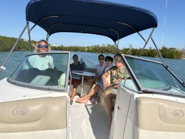 A group of friends enjoys a sunny day on the water, relaxing aboard a boat while navigating through scenic waterways.