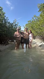 A cheerful group enjoys a fun day in the mangroves, wading through shallow waters and celebrating together — perfect for family adventures and nature exploration.