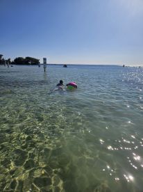 Two children enjoy a fun day swimming in shallow, clear waters, surrounded by a beautiful beach setting — perfect for family outings and water activities.
