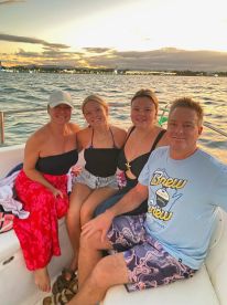 A joyful group enjoys a sunset cruise on the water, capturing a perfect moment of togetherness and celebration.