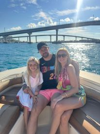 A happy family enjoys a sunny day on the boat, capturing a perfect moment with the beautiful water and bridge in the background — ideal for family outings and memorable experiences on the water.