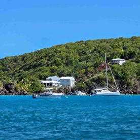 A scenic view of a catamaran and a motorboat docked near a lush green hillside, showcasing the beauty of a tropical getaway.