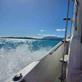 A stunning view of a boat cutting through sparkling turquoise waters, showcasing the beauty of the ocean and surrounding mountains.