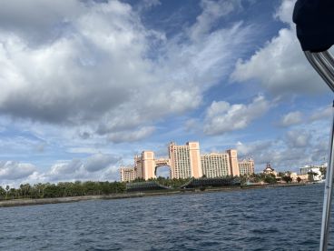 A scenic view of the iconic Atlantis Resort from the water, showcasing its stunning architecture against a backdrop of blue skies and clouds — a perfect destination for travelers in the Bahamas.