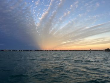 A stunning sunset casts vibrant colors over the coastline, creating a picturesque scene perfect for evening boat cruises.