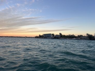 A serene sunset view over the water, showcasing a beautiful coastline with modern homes — perfect for capturing the tranquility of a boating experience.