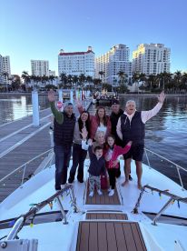 A joyful family gathers on the deck of a boat, waving and celebrating together at the dock — perfect for memorable family outings and gatherings.