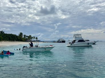A lively scene at the beach with guests enjoying the water and boats anchored nearby, perfect for a day of fun and relaxation on the water.