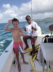 A joyful child proudly holds up a fish while fishing on a boat, accompanied by an enthusiastic adult — a perfect moment capturing the excitement of a day on the water.