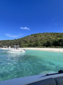 A scenic view of a group enjoying a day on the water, with boats anchored near a beautiful beach and crystal-clear turquoise waters — perfect for a relaxing getaway.
