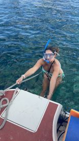 A woman enjoys snorkeling in clear waters, pulling herself up from the water while experiencing the beauty of marine life — a perfect moment for adventure seekers.