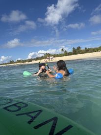 A couple enjoys snorkeling in clear waters, capturing memories with a camera while surrounded by a beautiful beach backdrop — a perfect day for aquatic adventures.