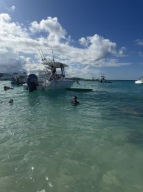 Guests enjoy a refreshing swim in crystal-clear waters near a fishing boat, perfect for snorkeling adventures and fun in the sun.