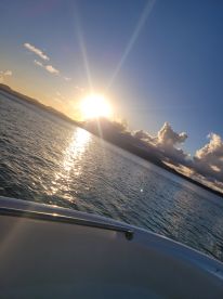 A stunning sunset view over the water, captured from the deck of a boat, showcasing the tranquil beauty of the evening sky.