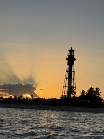 A stunning sunset view featuring a lighthouse silhouetted against the vibrant sky, perfect for capturing the beauty of coastal landscapes.