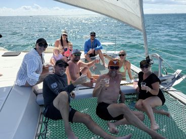 A joyful group enjoys drinks on a catamaran, celebrating together in the sun — perfect for family outings and memorable adventures on the water.