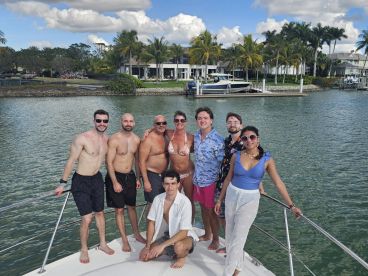 A lively group of friends poses on the bow of a boat, enjoying a sunny day on the water — perfect for celebrations and memorable outings.