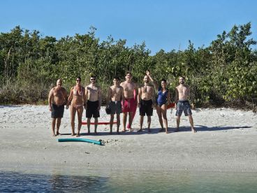 A cheerful group poses on the beach, ready for a day of fun in the sun — perfect for beach outings and group adventures.