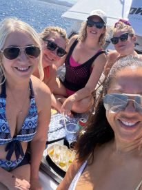 A fun group of friends enjoys a sunny day on the water, celebrating with drinks and laughter aboard a boat — perfect for memorable outings and parties.