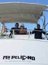 The friendly crew aboard the 'Mr Pelicano' boat welcomes guests for an inclusive tour experience, showcasing the vibrant atmosphere of boat adventures.
