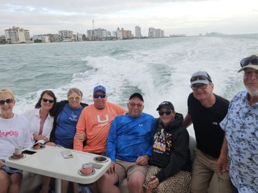 A cheerful group of friends enjoys a boat ride, capturing the essence of fun and camaraderie on the water with a scenic backdrop.