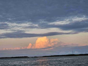 A stunning sunset over tranquil waters, showcasing vibrant clouds and a serene landscape — perfect for capturing the beauty of nature.