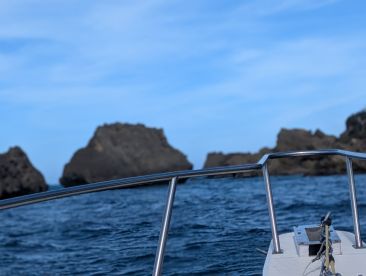 A view from the bow of a boat navigating through rocky waters, showcasing the vessel's sleek design against a backdrop of rugged cliffs.