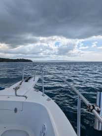 A scenic view from the front of a boat, showcasing the vast ocean and dramatic cloud formations — perfect for a day on the water.