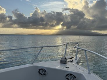 A serene view from the front of a yacht, showcasing tranquil waters and a stunning sunset backdrop — perfect for peaceful evening cruises.