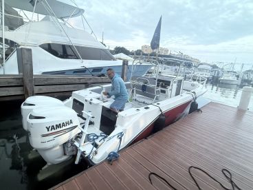 A man prepares equipment on a fishing boat at the dock, showcasing the vibrant marina atmosphere and readiness for a day on the water.