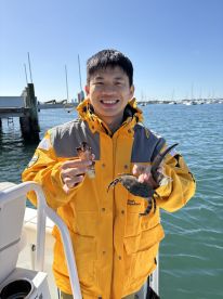 A smiling individual holds two crabs while enjoying a day on the water, showcasing a fun fishing experience. Perfect for marine enthusiasts and adventure seekers.