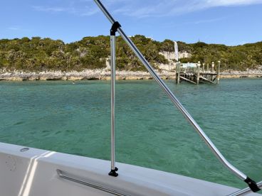 A scenic view from a boat showcasing a beautiful coastline and a dock, with a swimmer enjoying the clear waters — perfect for a day of relaxation and exploration.