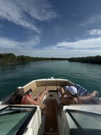 Two friends relax on the deck of a boat, enjoying the serene waters surrounded by lush mangroves — a perfect getaway for relaxation and nature exploration.