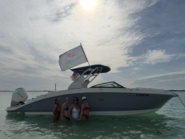 A group of friends poses in the water next to a stylish boat, celebrating a fun day on the water. Perfect for summer outings and memorable adventures.