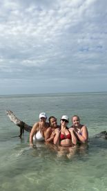 A joyful group of friends enjoys a fun day at the beach, posing together in shallow water — perfect for memorable summer adventures.