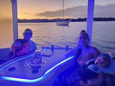 A family celebrates a birthday on a boat at sunset, enjoying cake and quality time together — a perfect moment for creating lasting memories on the water.