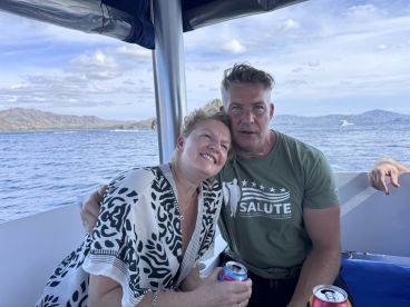 A couple enjoys drinks together on a boat, capturing a joyful moment amidst stunning ocean views — perfect for romantic getaways or celebrations.