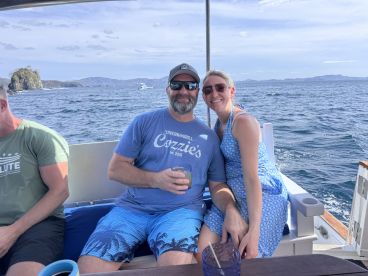 A cheerful couple enjoys drinks together on a boat, surrounded by stunning ocean views — perfect for romantic getaways or celebrations on the water.